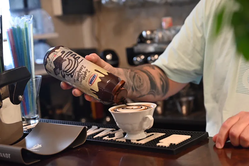Barista περιχύνει σιρόπι σοκολάτας σε cappuccino