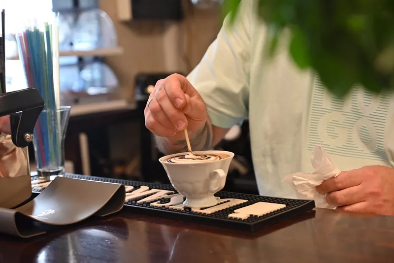 Barista ανακατεύει cappuccino με σχέδιο σοκολάτας